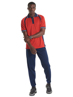 Person wearing Uneek Clothing UC123 Sports Poloshirt in red with short sleeves, collar and three button plackett and black and white panels on bottom of sleeves, shoulders, collar, plackett.