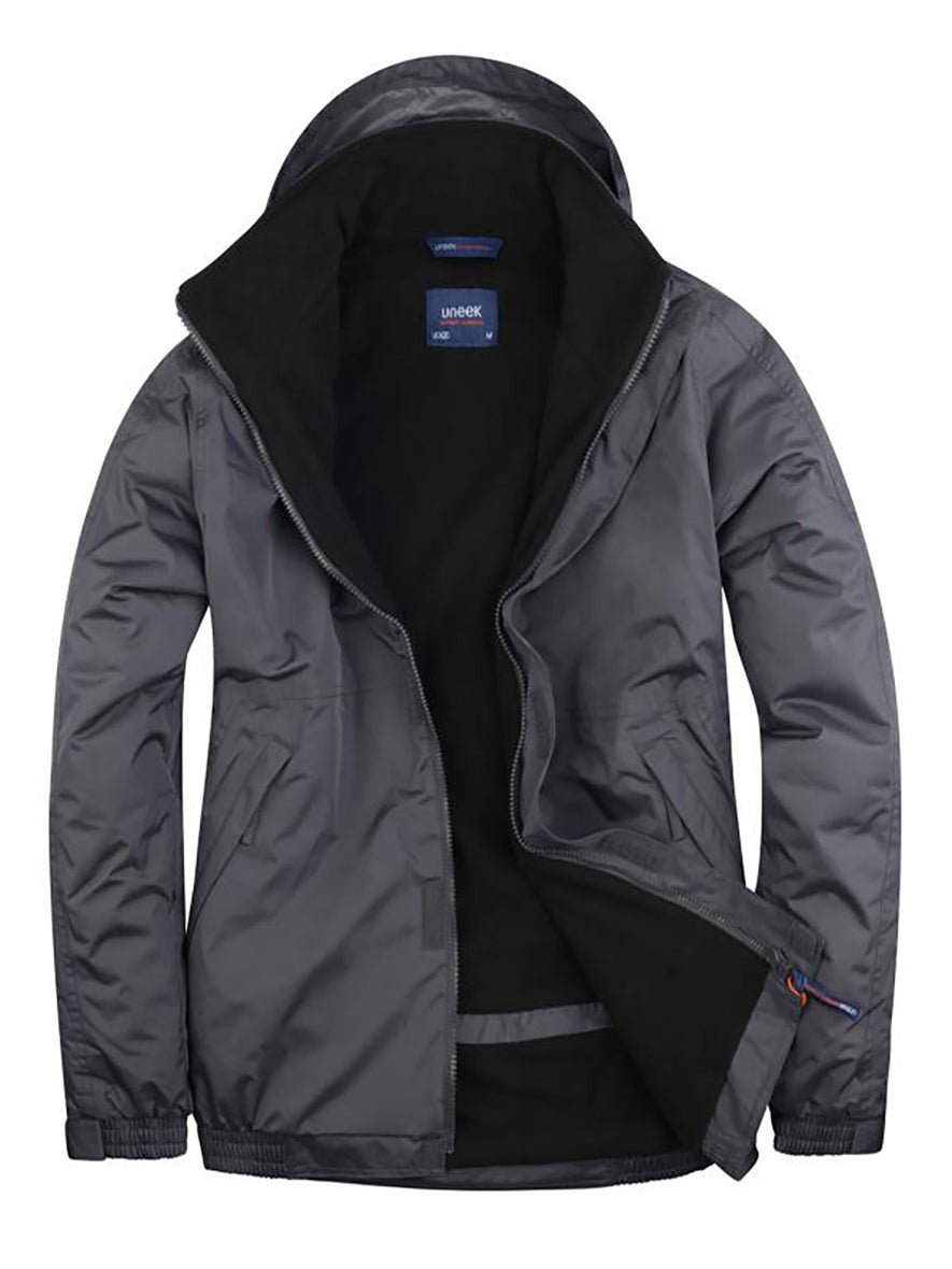 Uneek Clothing UC620 - Premium Outdoor Jacket in deep grey with hood with black fleece lining, full front zip and flap with velcro, two front lower pockets with flap concealed zip.