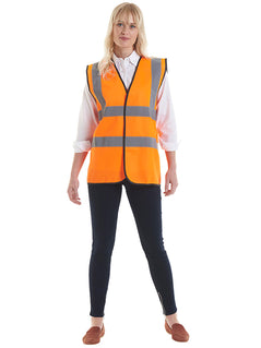 Person wearing Uneek Clothing UC801 - Sleeveless Safety Waist Coat in orange with black piping around edge and two strips of reflective tape across chest and one over each shoulder, velcro fastening.