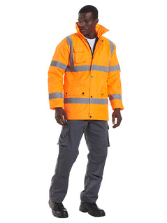 Person wearing Uneek Clothing UC803 - Road Safety Jacket in orange with two strips of reflective tape across chest and one over each shoulder and two strips on each arm, collar and full zip with flap and poppers. Pockets with flaps and poppers on right chest and two on lower front.