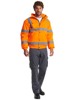 Person wearing Uneek Clothing UC804 - High Visibility Bomber Jacket in orange with two strips of reflective tape across chest and one over each shoulder and two strips on each arm, collar and full zip with flap and poppers, elasticated bottom of jackets and sleeves. Pockets with flaps on right chest and two on lower front.