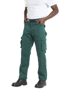Person wearing Uneek Clothing UC906 Super Pro Trouser in bottle green with belt loops, button and zip fastening at waist, two side pockets with holster pockets and two pockets on side of legs with flaps. Knee pad patches on both knees