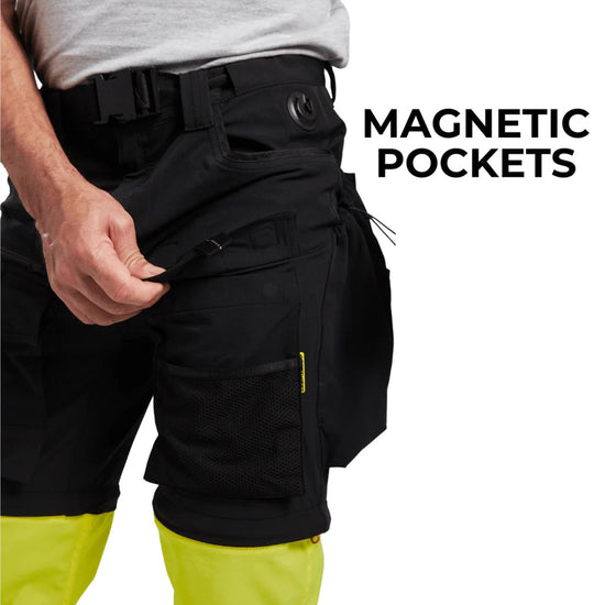 Person wearing Portwest Ultimate Modular 3-in-1 Trousers with black shorts top half and multiple pockets, belt and belt loops and fluorescent yellow hi-vis trousers on bottom half. Showing off the clip on button built into trousers and text saying ' magnetic pockets'.